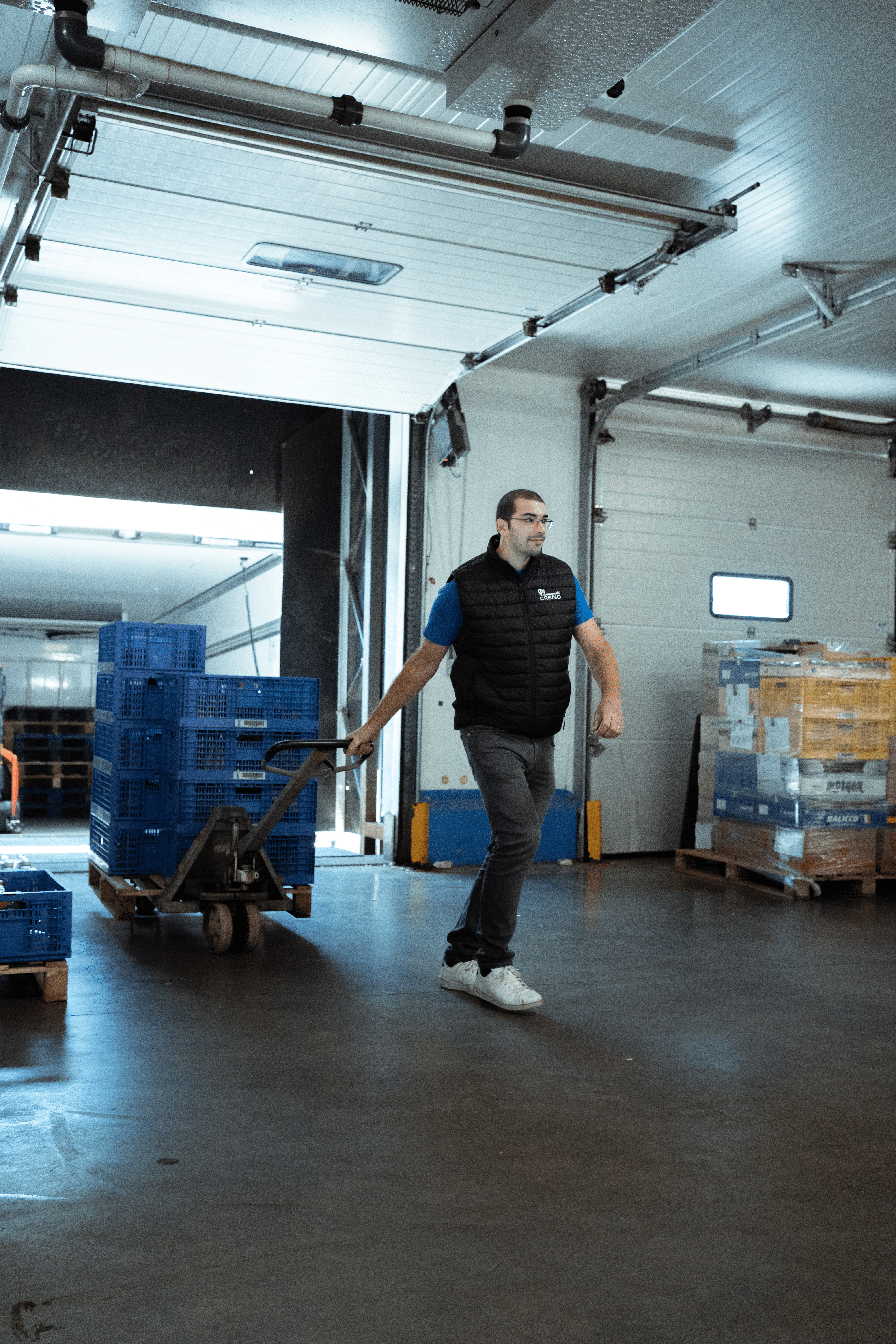 Un travailleur tire un chariot dans un entrepôt